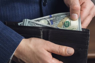 Erkek işçilerin yakın plan fotoğrafları cüzdan, iş ve finans konseptinden 100 dolarlık banknotlar alıyor