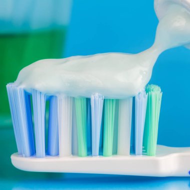 Diş fırçasında diş macunu, yeşil diş fırçası, mavi arka planda diş macunu tüpü, ön plana odaklan, makro resim