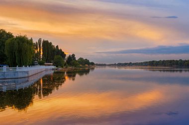 Nehirde portakal rengi günbatımı manzarası, dramatik akşam gökyüzü suya yansıyor, Khmelnytskyi, Ukrayna.