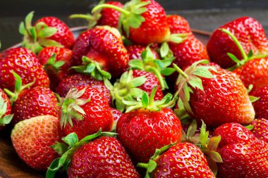 Tabaktaki taze organik çilekler. Koyu ahşap arka planda..