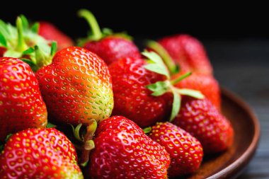 Siyah arka planda izole edilmiş taze organik çilek hasadı.