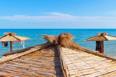 Yaz güneşli bir günde plajın tepesinde saman şemsiyeler..