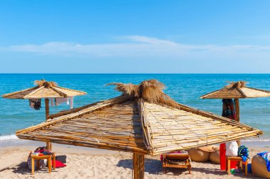 Yaz güneşli bir günde plajın tepesinde saman şemsiyeler..