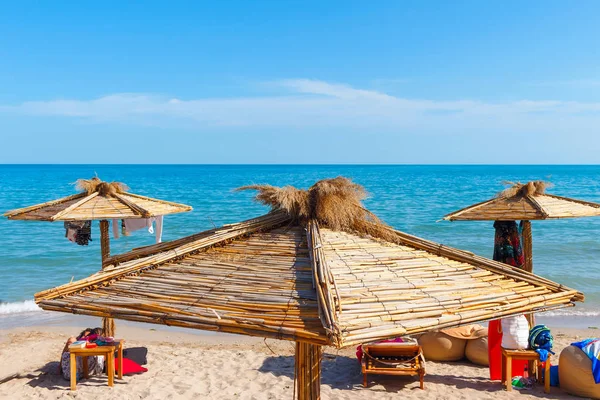 Yaz güneşli bir günde plajın tepesinde saman şemsiyeler..