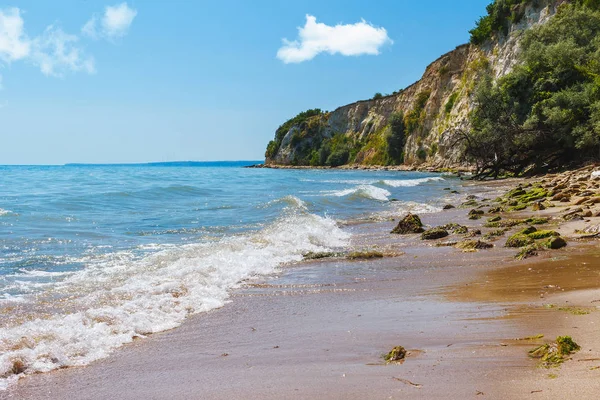 Karadeniz kıyısı, kumsalda taşlı deniz manzarası, gök mavisi suların üzerindeki kayalıklar, küçük dalgalar, mavi gökyüzü..