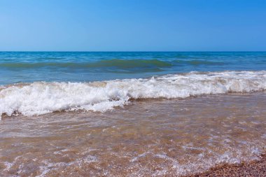 Karadeniz kıyısı, kumlu deniz manzarası, küçük dalgalar, masmavi su, mavi gökyüzü, yaz uykusu konsepti..