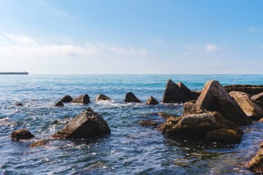 Karadeniz kıyısında deniz manzarası, ön planda güneşli yaz gününde mavi suda büyük taşlar..