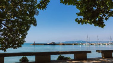 Bulgaristan 'ın Karadeniz kıyısındaki Balchik kasabasındaki sokaktan ağaç yaprakları arasından denizi izle.