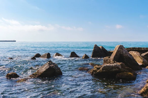 Karadeniz kıyısında deniz manzarası, ön planda güneşli yaz gününde mavi suda büyük taşlar..