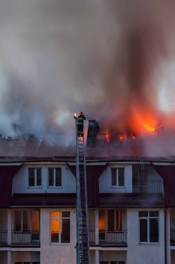 Şehrin çatısı dumanla alev alev yanıyor. İtfaiyeci ya da itfaiyeci yangını söndürüyor..