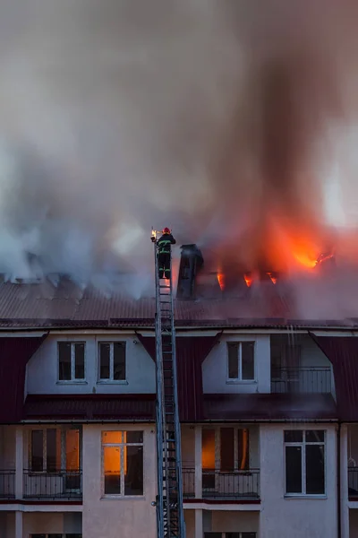 Şehrin çatısı dumanla alev alev yanıyor. İtfaiyeci ya da itfaiyeci yangını söndürüyor..