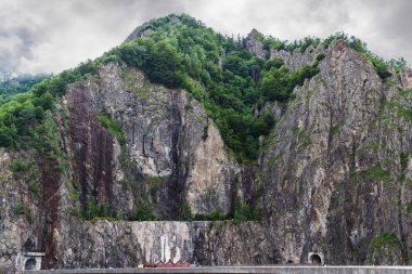 Romanya 'nın Carpathian dağlarındaki kayalık Fagaras kayalıkları, Vidraru barajı ve gölünde yer alan yol tüneli ile yüksek uçurum.