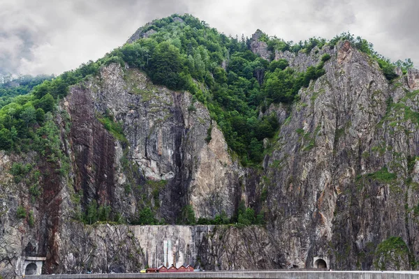 Romanya 'nın Carpathian dağlarındaki kayalık Fagaras kayalıkları, Vidraru barajı ve gölünde yer alan yol tüneli ile yüksek uçurum.