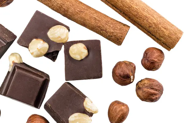 Fındıklı ve tarçınlı acı siyah çikolata parçaları beyaz arka planda izole edilmiş..