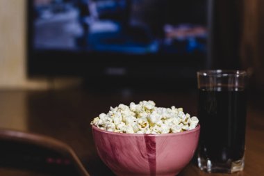Kasede patlamış mısır ve film izlemek için karanlık odadaki ahşap masada kola..