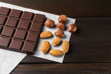 Acı, koyu çikolata, badem ve fındık ahşap arka plan üzerinde.