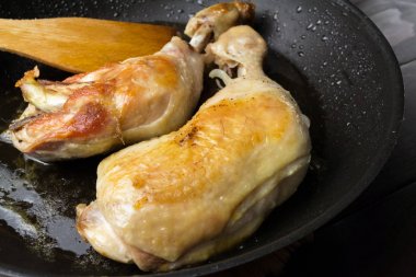 İki kızarmış tavuk budu siyah tavada, yakından görmek.