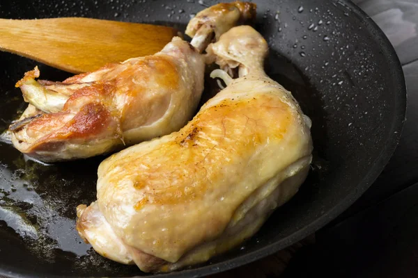 İki kızarmış tavuk budu siyah tavada, yakından görmek.