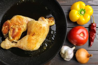 Sebze ve baharat koyu ahşap plakalar, üstten görünüm üzerinde siyah tavada iki kavrulmuş tavuk budu.