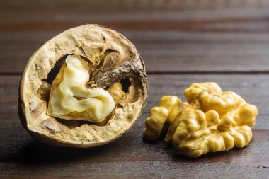 Yarım ceviz çekirdek ve yarım ceviz kabuğu koyu ahşap arka plan üzerinde.