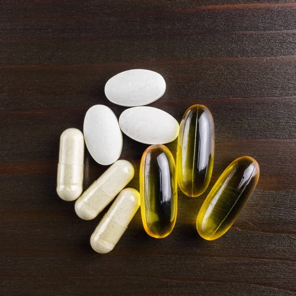 复合维生素和膳食补充剂 黄胶囊欧米加3 蛋氨酸的白色 钙药片在木制桌子上 顶部视图 — 图库照片