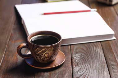 Kahverengi fincanda sıcak siyah kahve koyu ahşap çalışma masasında beyaz çarşaflar not defterinde, seçici odaklı..