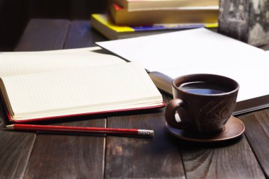 Beyaz temiz sayfalı not defteri, koyu kahve fincanı, kırmızı kalem, koyu ahşap çalışma masası, çalışma veya çalışma konsepti.