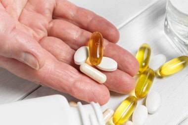 Kadın el bilgisayarı vitamin kompleksi ve beslenme takviyesi, sarı kapsüller omega 3, beyaz kalsiyum ve glukozamin hapları, bir bardak su ahşap masa..