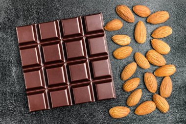 Karanlık, acı çikolata bar ve badem fındık siyah deri arka plan, üstten görünüm doku.