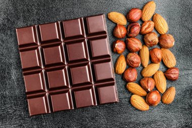 Karanlık, acı çikolata, badem ve fındık siyah deri doku arka plan üzerinde ana sayfa görünümü.