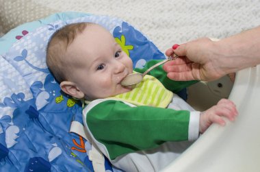 Küçük çocuk bir kaşıkla yiyor. Yakın çekim.