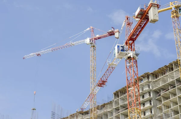 Arrows of three cranes above a concrete monolithic building unde — Stock Photo, Image