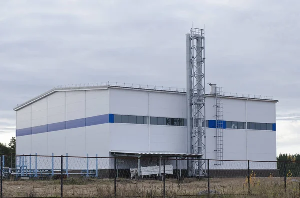 Bâtiment industriel blanc avec tuyaux de ventilation contre un nuage — Photo