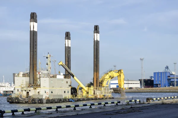 Krachtige drijvende graafmachine op vier zwarte vijvers in de zeehaven. — Stockfoto