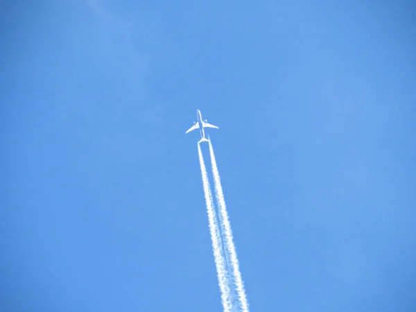 Літаючий літак зі смугами повітряної стежки — стокове фото