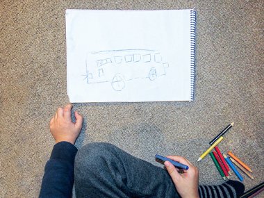 Küçük çocuk bir kağıt üzerinde bir otobüs boyama