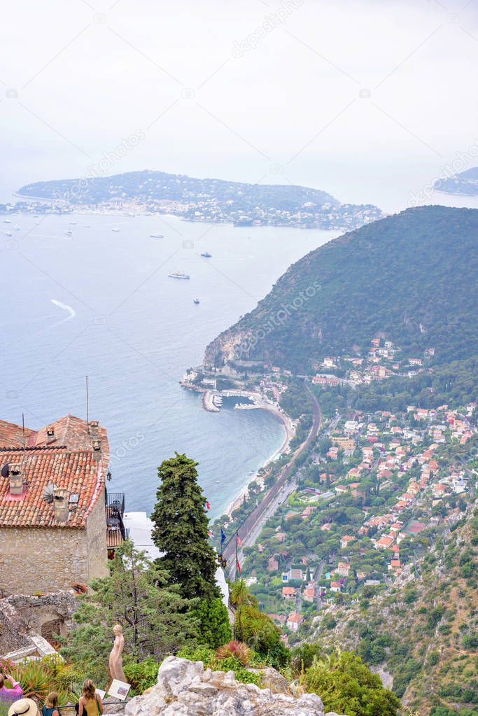 Daylight foggy view to Eze village, Mediterranean sea, trees and