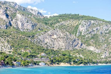Deniz kıyısı, yeşil ağaçlar ve büyük ro yakınındaki binaların görünümüne gün ışığı