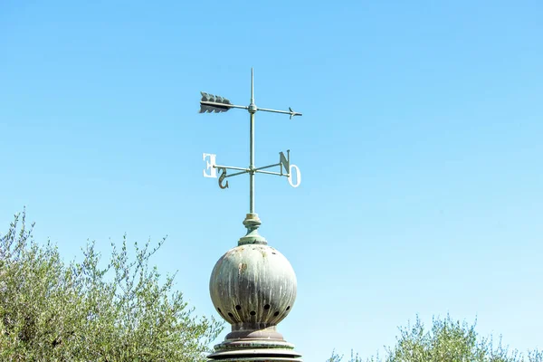 Vista de la luz del día al viejo indicador de dirección del viento con aguja cardinal — Foto de Stock