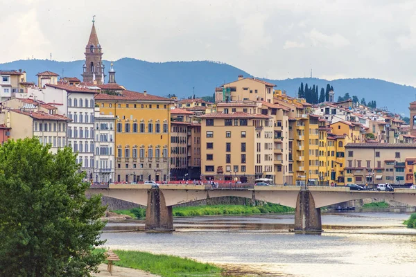 Dagsljus molnig dag Visa till bron över floden Arno med människor — Stockfoto