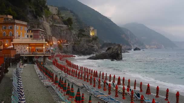 伞在海滩在蒙泰罗索 五渔村 意大利 海以波浪和山在雾在地平线 晚上灯 — 图库视频影像