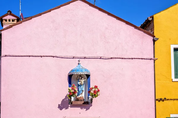 Vue de la lumière du jour à la façade vibrante de la maison rose avec statue de Jésus — Photo