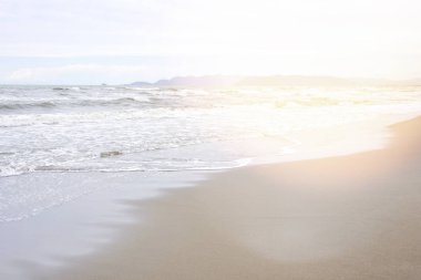 Ayak izleri ve yükselen w ile kum sahil görünümünden gün ışığı