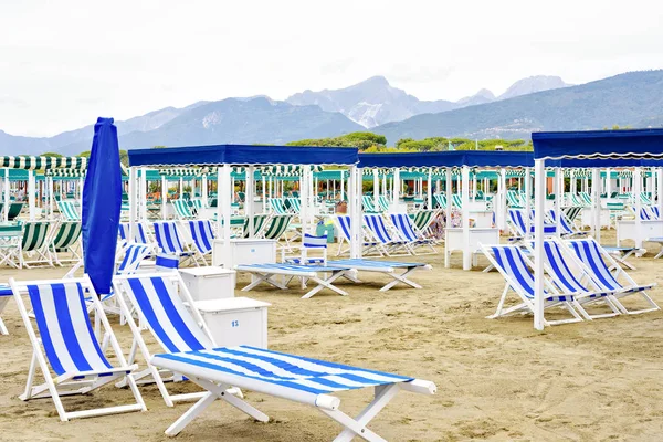 Nyári megtekintése élénk kék sunchairs és napernyők a strandon. — Stock Fotó