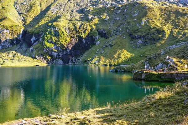 Vista de la luz del día al lago Balea con montañas verdes que reflejan en w — Foto de Stock
