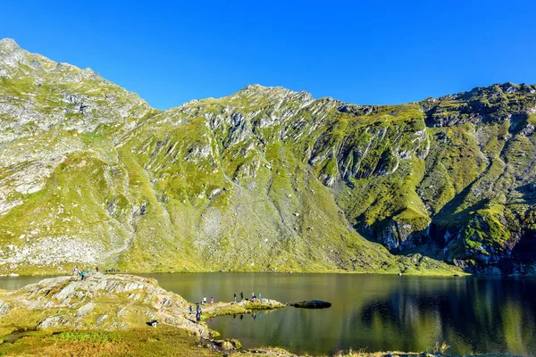 Vista de la luz del día al lago Balea con montañas verdes que reflejan en w — Foto de Stock