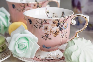 Çiçekli süs ve badem kurabiyeli pembe çay fincanları.