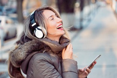 Telsiz kulaklıkla müzik dinleyen mutlu bir kadın.