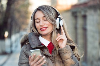 Telsiz kulaklıkla müzik dinleyen mutlu bir kadın.