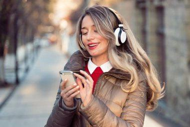 Telsiz kulaklıkla müzik dinleyen mutlu bir kadın.